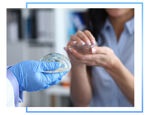 Clinic visit and female breast implant selection. Close-up, doctor`s hands in gloves holding female breast implant. Young woman is holding female breast silicone implant in her hands.