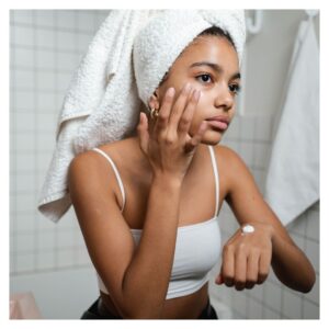 a young woman applying moisturizer